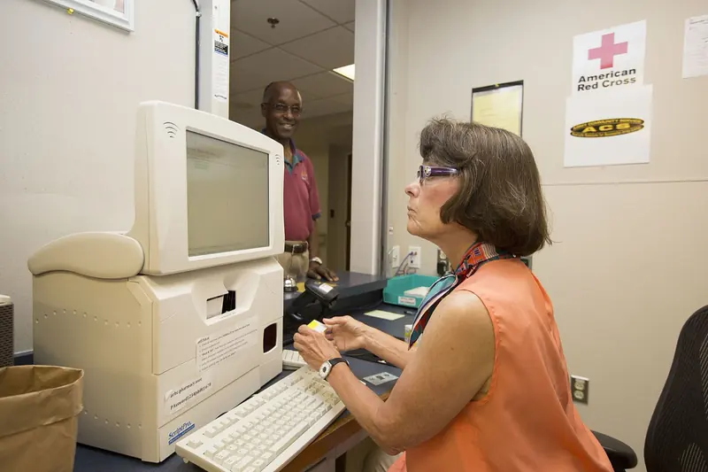 Farmacêutica registra uma receita no computador do balcão de uma farmácia